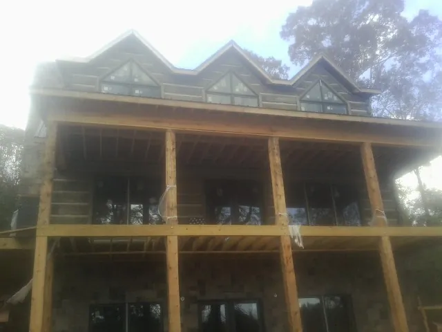 Dormers and porch framing on a large log home under construction — Roof Coating work by our crew in Pandora