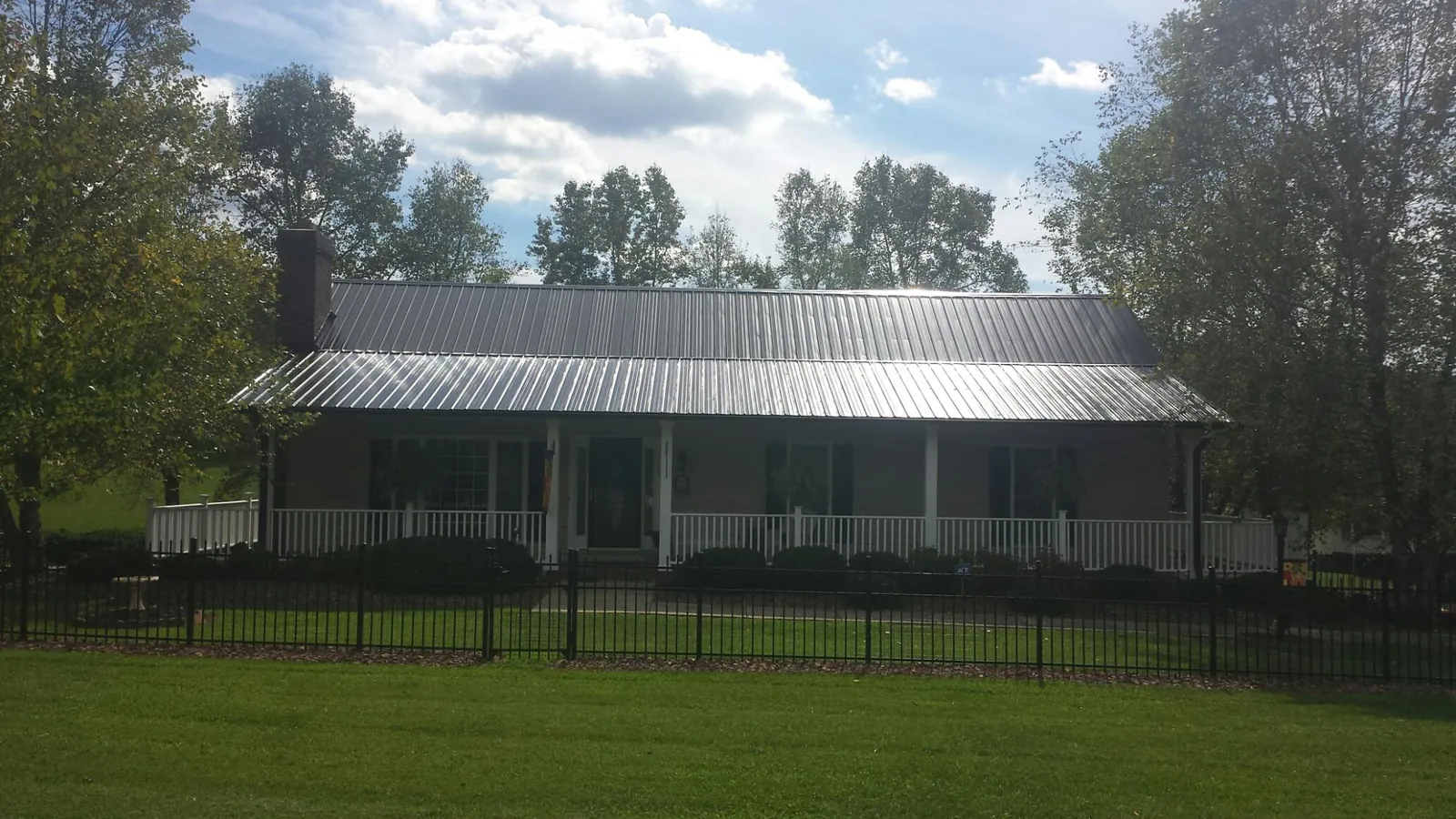 Gray metal roof on a brick ranch with a full width front porch — Gutter Guard Installation work by our crew in Pandora