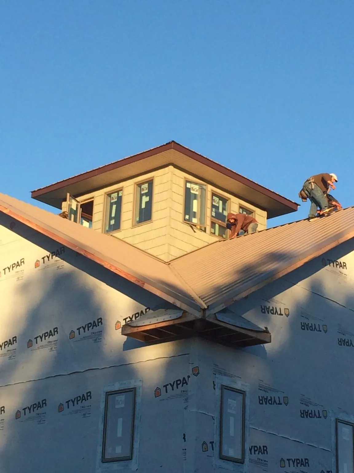 Roofers working around a rooftop cupola on a new metal roof at sunset — Roof Waterproofing in Pandora by Roofing Brothers